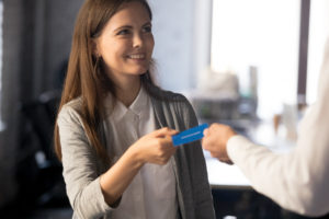 Male boss give business card to excited female worker or employee, exchanging contacts or information with partner, businessman introducing present identification ticket or record to woman colleague