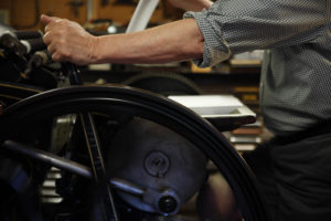 A printer works the flywheel of an antique letterpress machine in his studio.