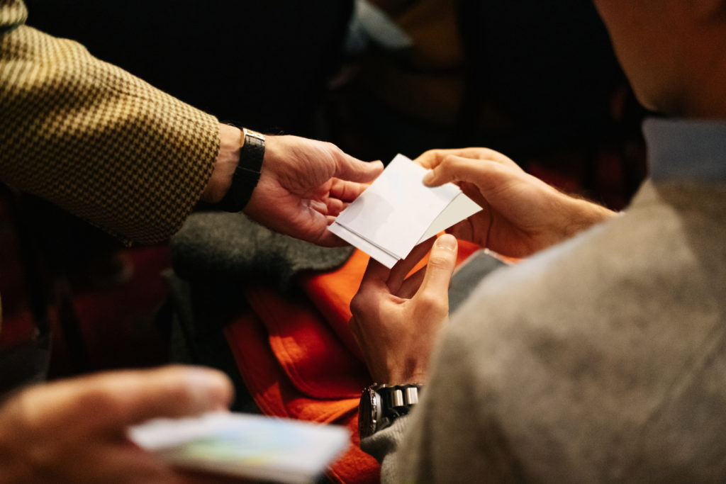 Two people hand over business cards at a meeting