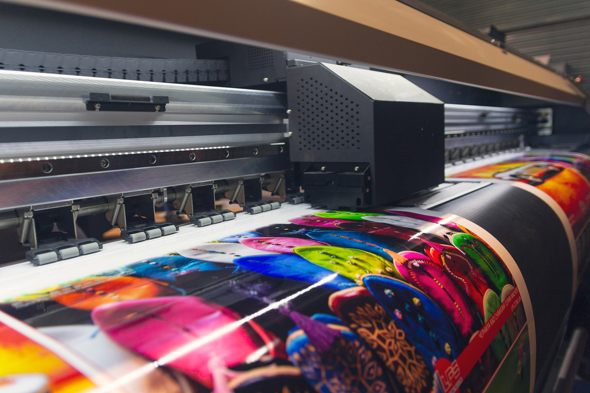 An industrial printer printing out a large, colorful poster in El Paso.